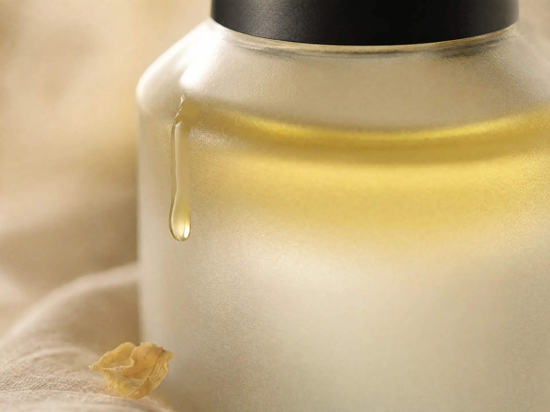 Macro detail of golden body oil on frosted glass